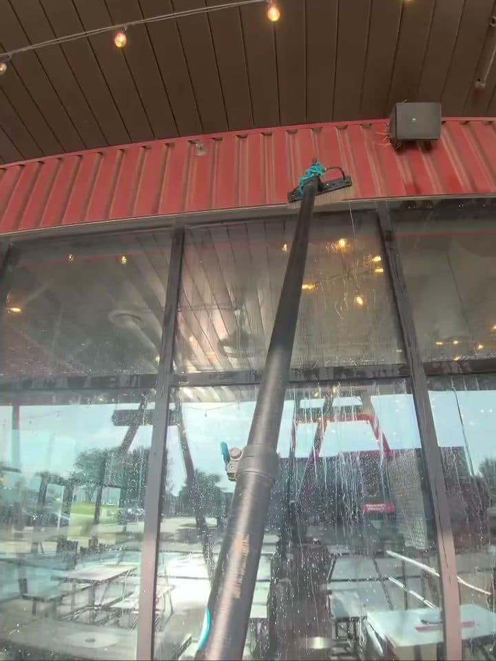 On The Spot technician cleaning a commercial storefront window with a water-fed pole